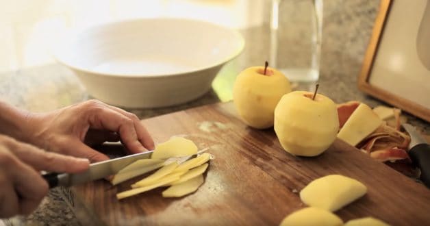 Slicing apples paper thin on a cutting board for a French Apple Tart Recipe