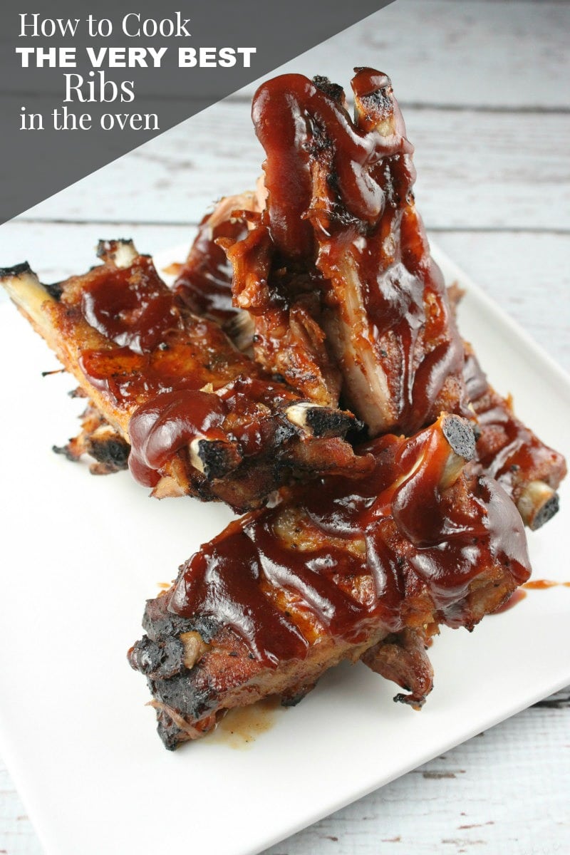 ribs on a white plate with barbecue sauce drizzled on top