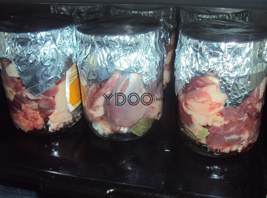 стеклянные банки с утиным мясом, накрытые сверху фольгой, на противне в духовке