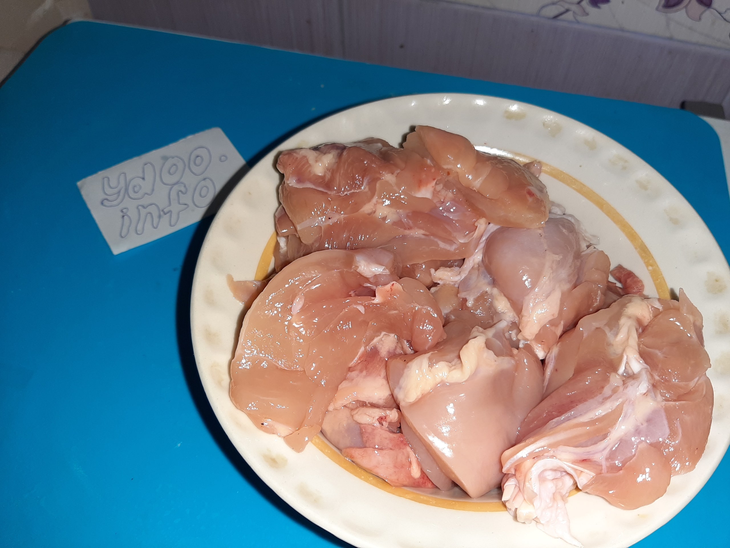 сырые кусочки куриных бедер в тарелке на кухонном столе