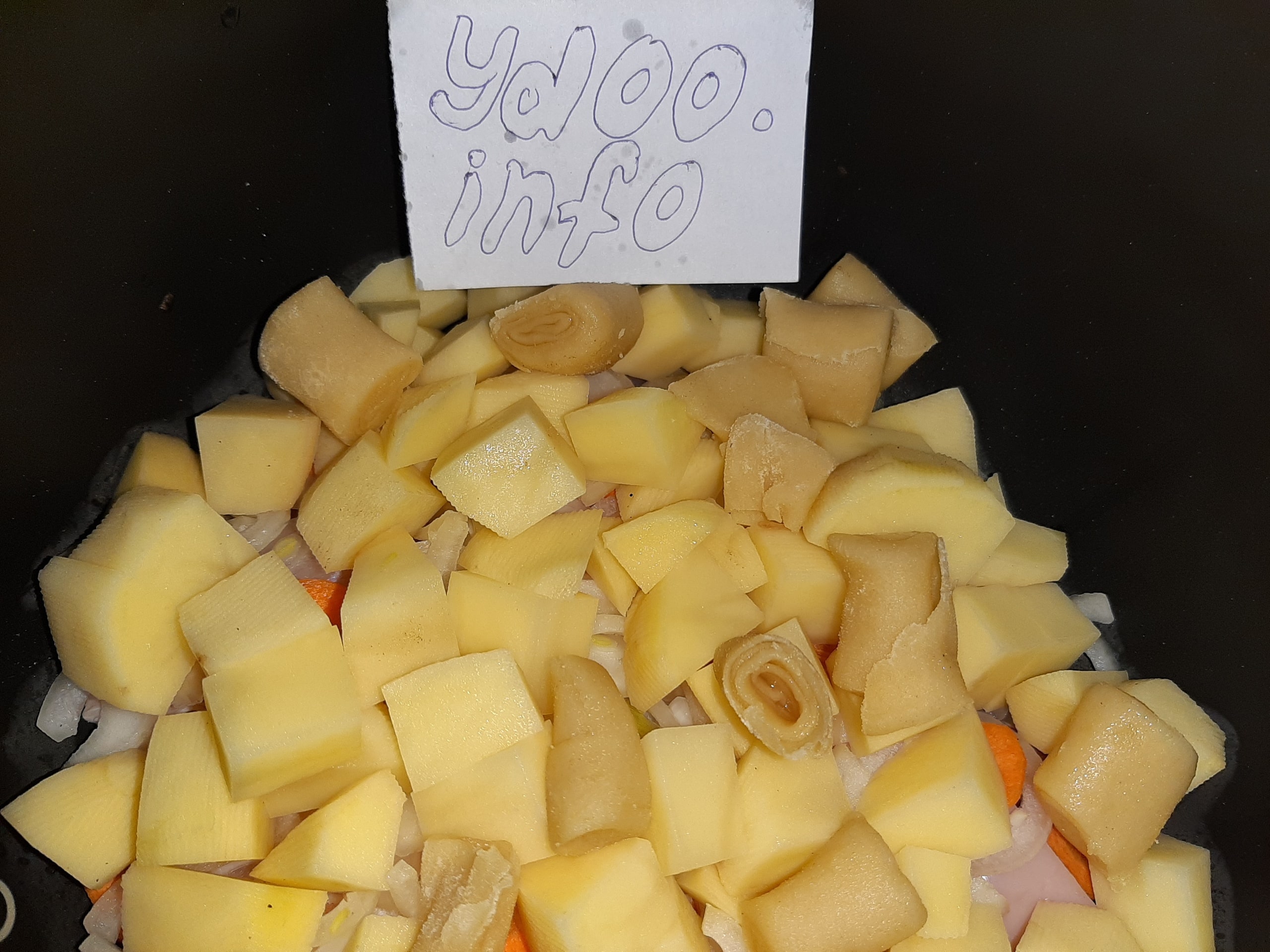 кубики картофеля, нарезанные морковь и лук с кусочками теста в казане